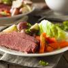 A plate has pices of corned beef, carrots, cabbage and potatoes.