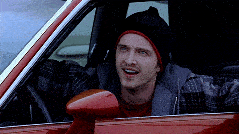 A man sitting in a car exclaims "what?" out the open window.