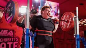 A power lifter screams as they reach the top of a squat with 490 pounds on the bar.