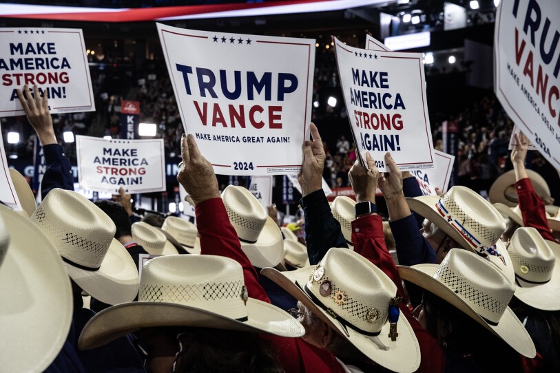 People in cowboy hats hold up "Trump, Vance" signs on the convention floor.
