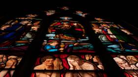 Stained glass window with the souls damed in hell at the bottom.