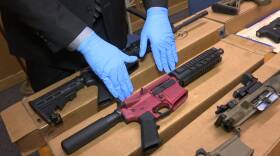 Hands in latex globes show of large-capacity weapons at a press conference