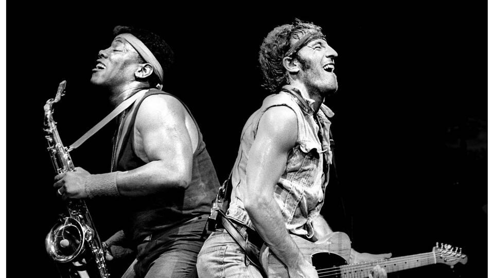 Legendary rockers Bruce Springsteen and Clarence Clemens, back to back, play the saxophone and guitar.