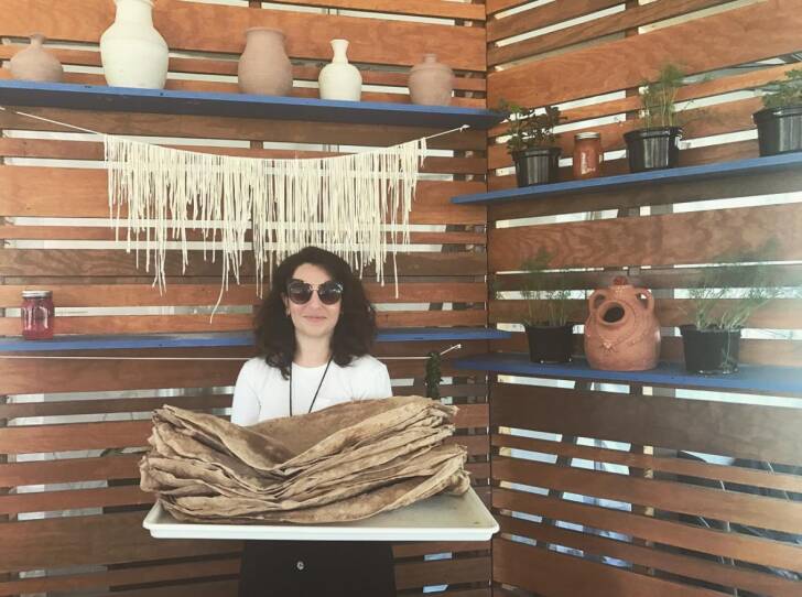 A woman poses with a massive tray of flatbreads.