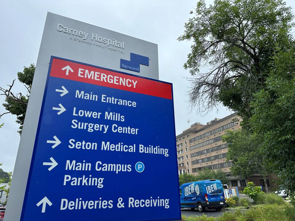 A sign points to various entrances of Carney Hospital.