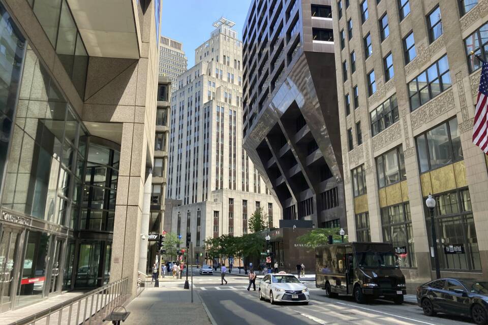 Tall office buildings line both sides of a one-way street in downtown Boston.
