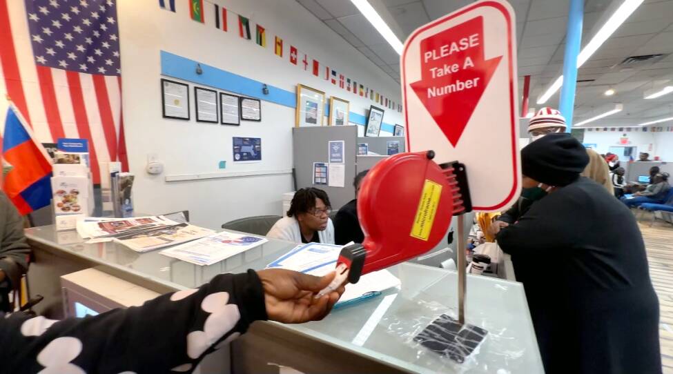 A hand reaches out to take a number by a services desk.