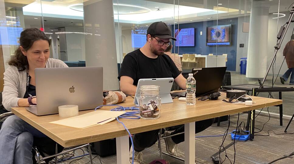 Frederique Rigoulot and Andrew Vanasse edit video footage at a table on their laptops