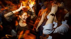 A women dances and smiles in a crowded nightclub surrounded by people.
