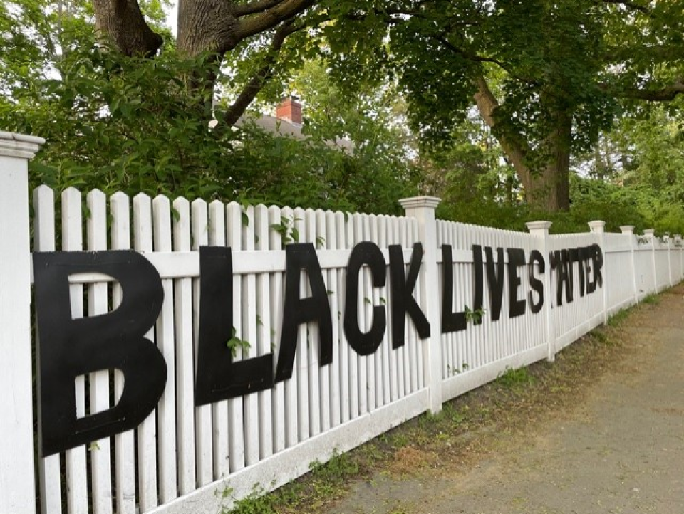 Black letters spelling out Black Lives Matter hang on a white fence.