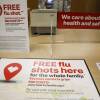 An infographic at a CVS table advertises free flu shots. A bottle of hand sanitizer is off to the side.