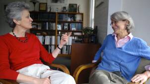 Two women sit in an office engaged in conversation