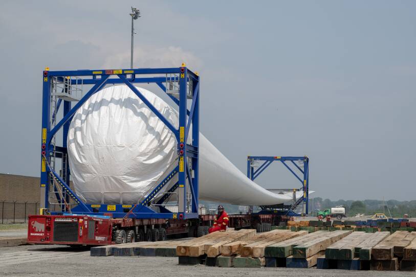 Workers help transport an offshore wind turbine blade before it is stacked on top of another at Vineyard Wind on Thursday, June 8, 2023, in New Bedford, Mass. (Raquel C. Zaldívar/New England News Collaborative)