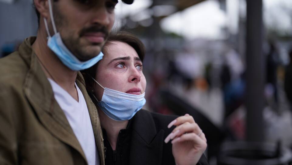 A couple holds each other, the woman looking distressed.