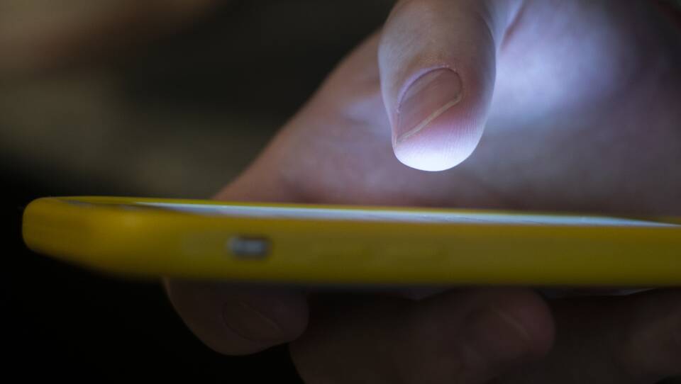 A person uses their thumb to type numbers on a smartphone.