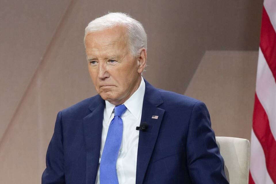 Biden looks somber while seated in a suit.