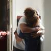 Rear view of female caregiver embracing while greeting man at home