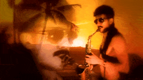A man with a mullet and sunglasses plays the saxophone seductively