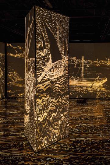 Large golden brush strokes are projected onto the ceiling, floor and walls of a large gallery space.