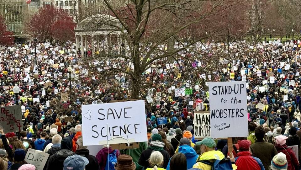 A large crowd on Boston Common holding signs that read "save science" and "stand up to the mobsters"