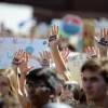 Hands raise above a protesting group with "OUR FUTURE IN YOUR HANDS" written on them in bold black writing. Many posters are visible, blurry, above the crowd.