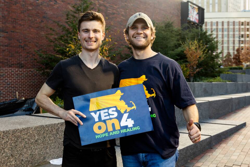 Two men stand side-by-side, holding a sign that says "Yes on 4: Hope and Healing"