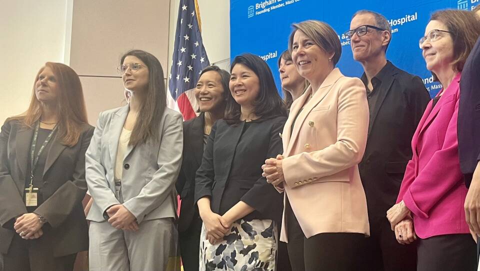 Governor Maura Healey, a woman with short brown hair wearing a pink blazer, stands among a group of people.