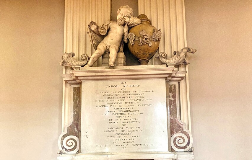 A marble memorial written in Latin and topped with a sculpture of a weeping child commemorates the life of Charles Apthorp.