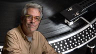 A photo of a man in glasses and a casual buttondown overlaid over a turntable