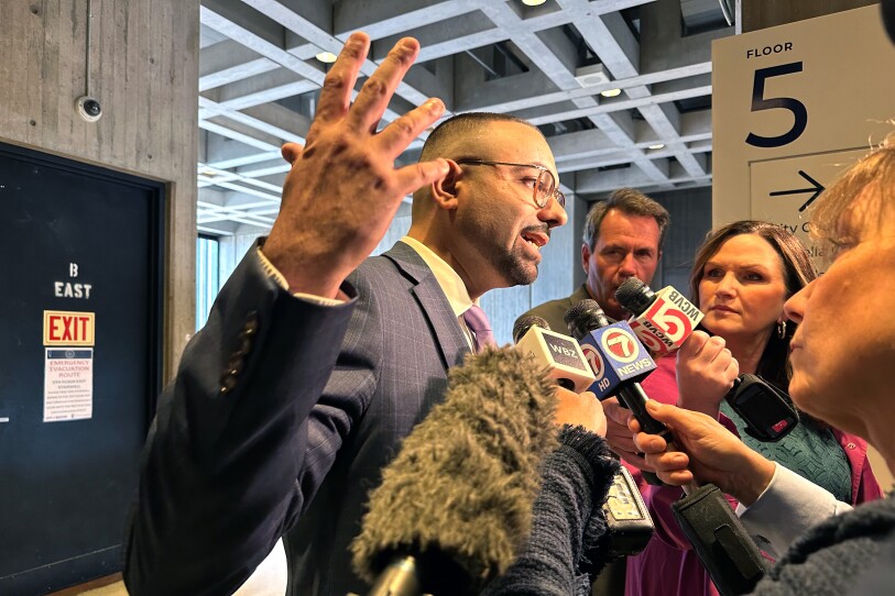 Ricardo Arroyo speaks into microphones animatedly as reporters hold them