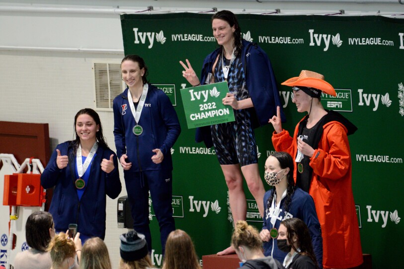 Swimmers stand on a podium.