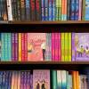 This is a photograph of a bookcase at a bookstore, which is three shelves full of romance novels, all of which have bright book covers