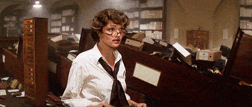 A woman removes her glasses and looks around in distress