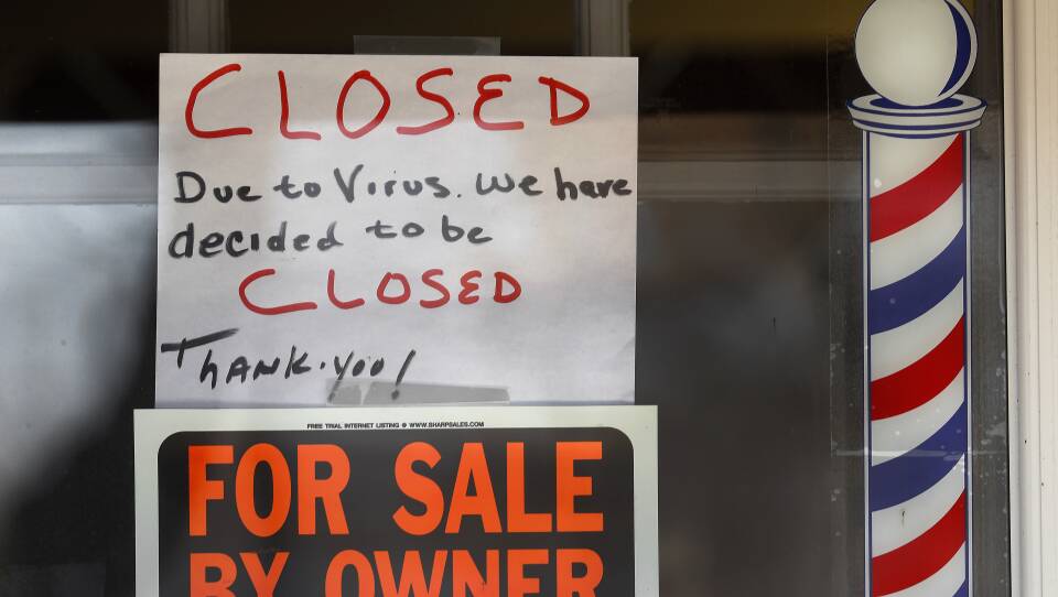 Signs are displayed in the window of a store in Grosse Pointe Woods, Mich. The Paycheck Protection Program, aimed at helping small businesses survive the coronavirus crisis, has been beset by problems.
