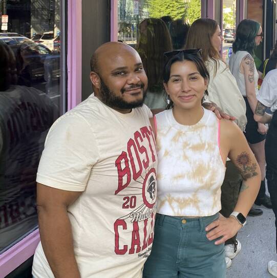 Two people posing for a photo outside Dani's Queer Bar.