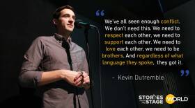 Dark-haired man in a black button-down shirt standing at a microphone