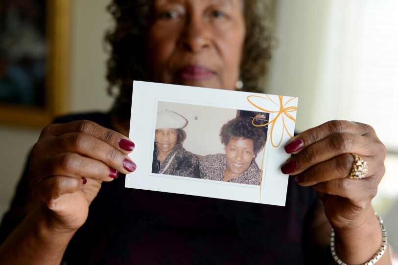 A women, out of focus, holds up an old photograph of two women