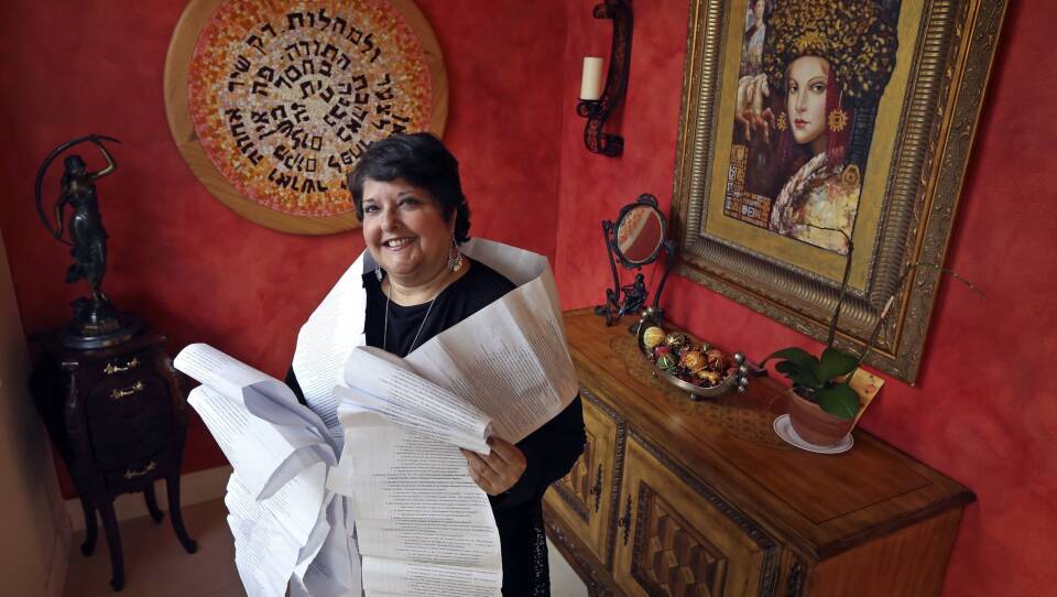 Genie Milgrom, pictured in 2013, stands in the entryway of her Miami home wrapped in a long family tree, filled with the names of 22 generations of grandmothers. Raised Catholic, Milgrom traced her family's hidden Jewish roots with the help of a trove of ancient family recipes written down by the women of her family over generations.