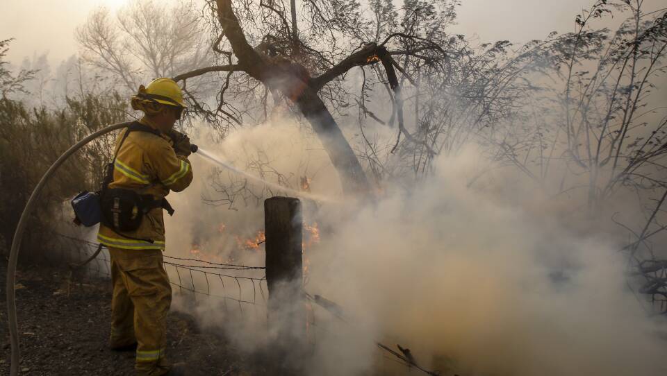 A firefighter battles a wildfire near a ranch in Simi Valley, Calif., on Wednesday. The large new wildfire erupted in wind-whipped Southern California, forcing the evacuation of the Ronald Reagan Presidential Library and nearby homes.