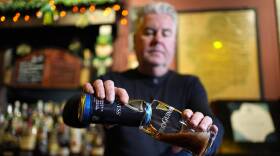 A man behind a bar pours a nonalcoholic beer.