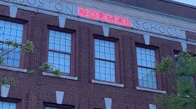 Bright neon lights up the word "Normal" in MassArt's original title "Boston Normal School"