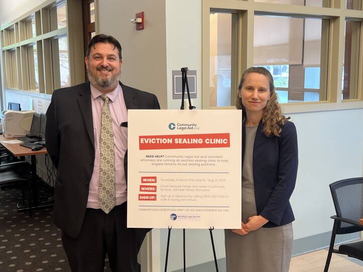 Two people stand alongside a sign.