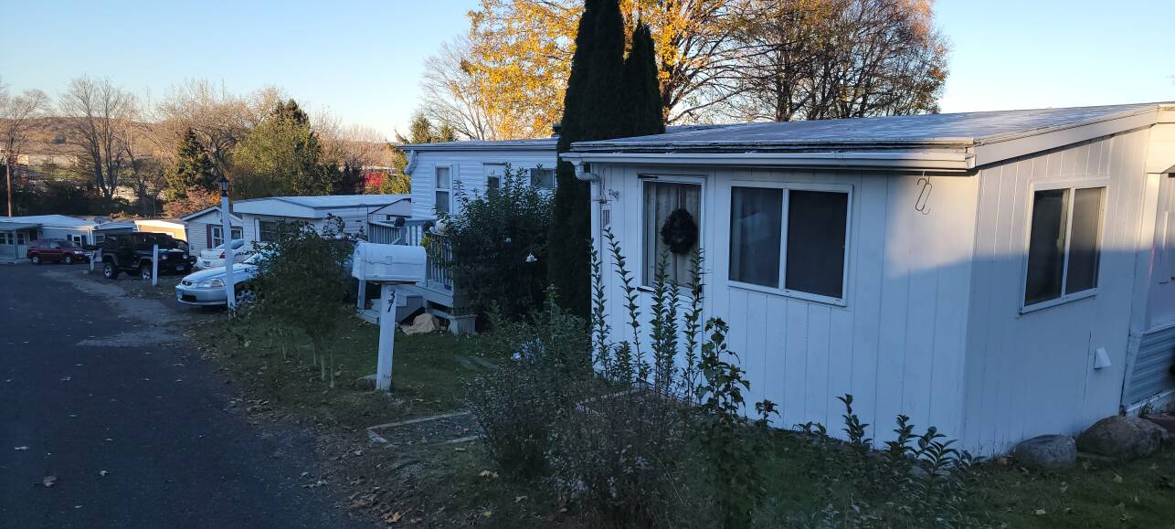 A row of small, white trailers line a paved road.