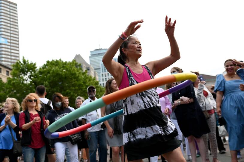 A woman swings a hula hoop around her waist.