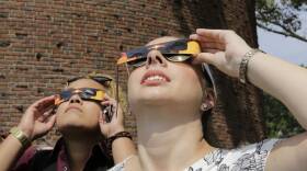Two young adults look up with eclipse glasses