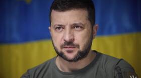 Volodymyr Zelenskyy in front of a Ukrainian flag.