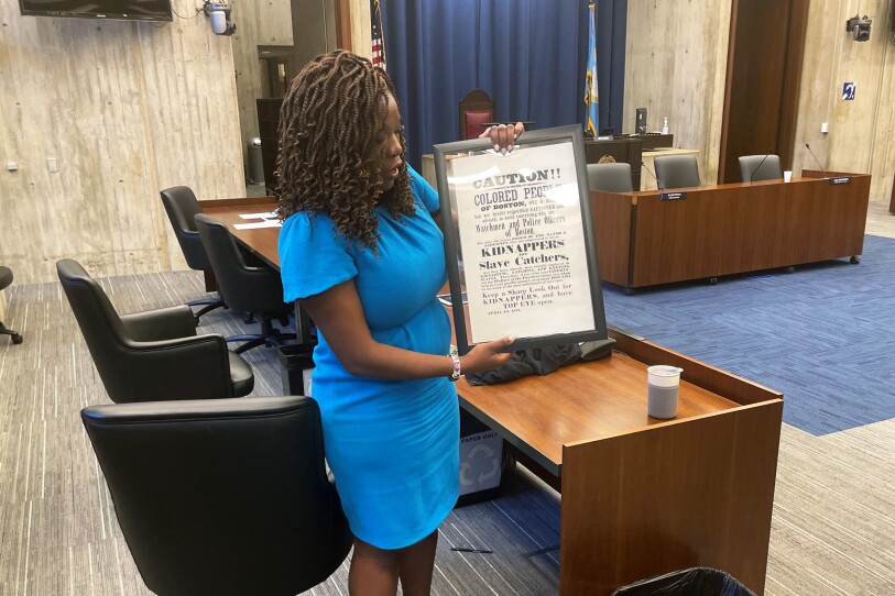 Boston City Councilor Ruthzee Louijeune holds a framed reprint of a poster that warned freed Blacks in Boston of local enforcement of the federal Fugitive Slave Act.