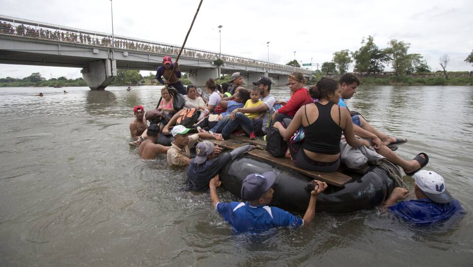 A group of Central American migrants cross the Suchiate River aboard a raft, on the the border between Guatemala and Mexico, in Ciudad Hidalgo, Mexico on Saturday. After Mexican authorities slowed access through the border bridge to a crawl, hundreds of migrants are boarding the rafts or wading across the river and crossing into Mexico illegally.