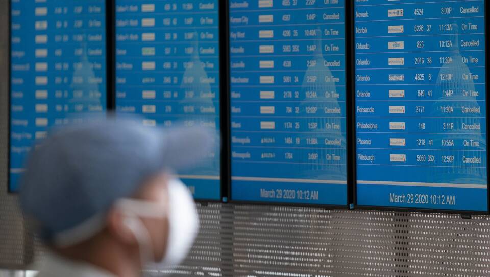 A traveler wearing a face mask looks at the flight board at Reagan National Airport last month in Washington, D.C.