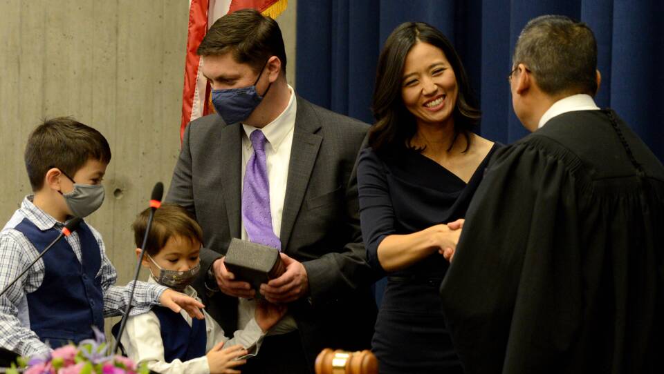 Wu smile and shakes hands with the judge after her swearing in while her husband and two sons stand behind her.